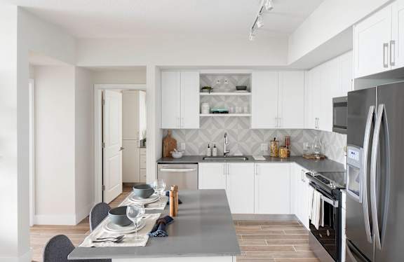 A modern kitchen with a dining table set for four. at Palma, Doral, FL