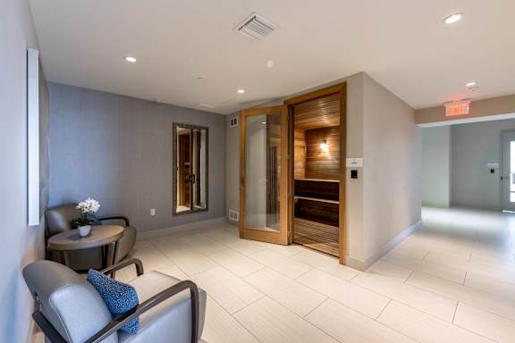 A modern living room with a grey sofa and a wooden door. at Palma, Doral, FL, 33166