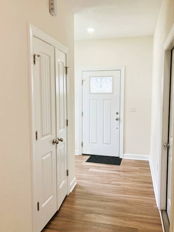A hallway with white doors and a black doormat.