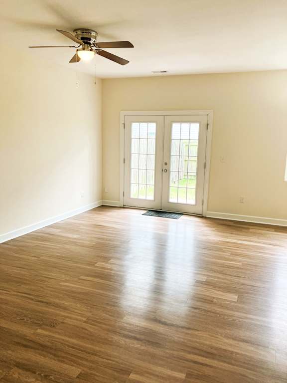 A room with a ceiling fan and wooden flooring.