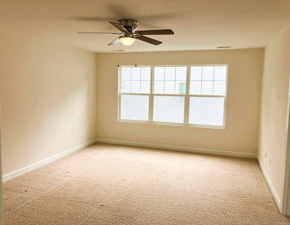A room with a ceiling fan and a window.