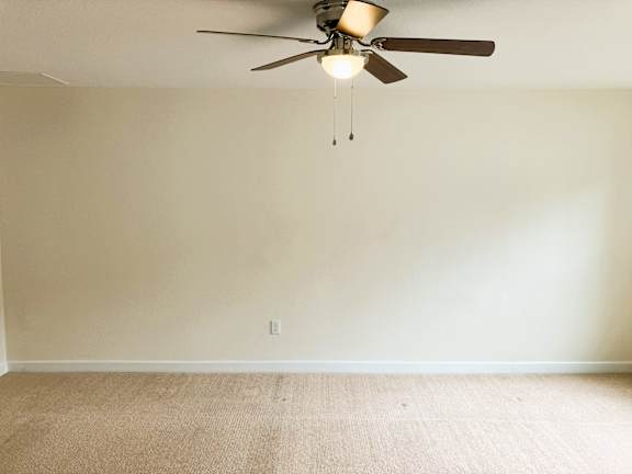 A room with a ceiling fan and carpeted floor.