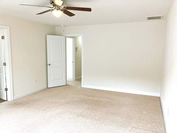 A room with a ceiling fan and carpeted floor.
