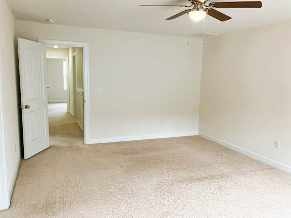 A room with a ceiling fan and carpeted floor.