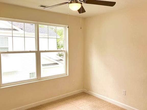 A room with a ceiling fan and a window.