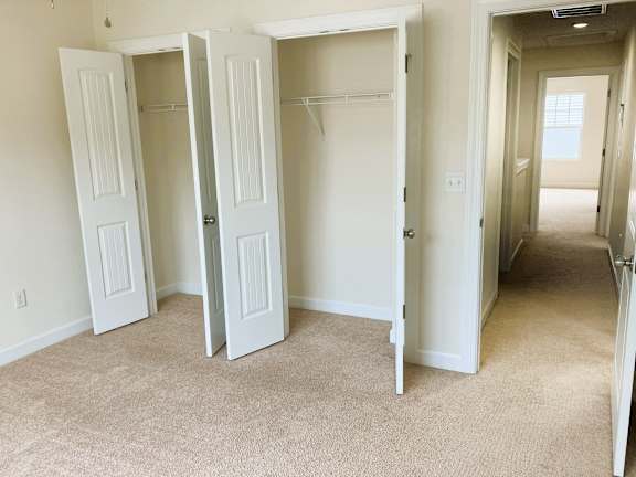 Three white doors open in a room with carpeted floor.
