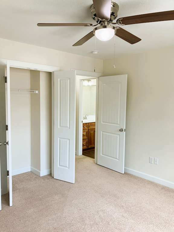 A room with a ceiling fan and carpeted floor.