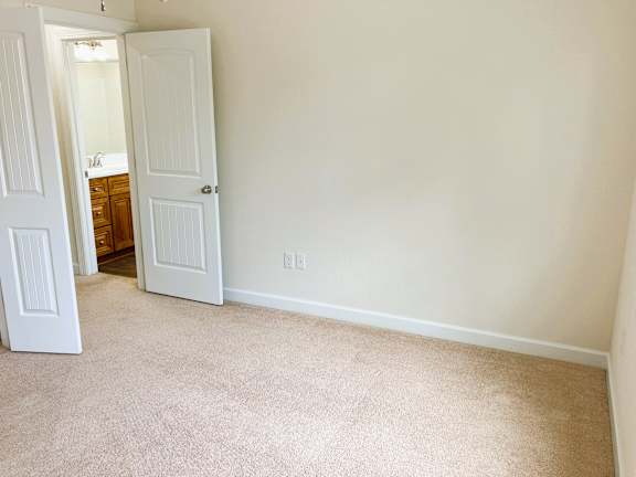 A white door is open to a room with a carpeted floor.