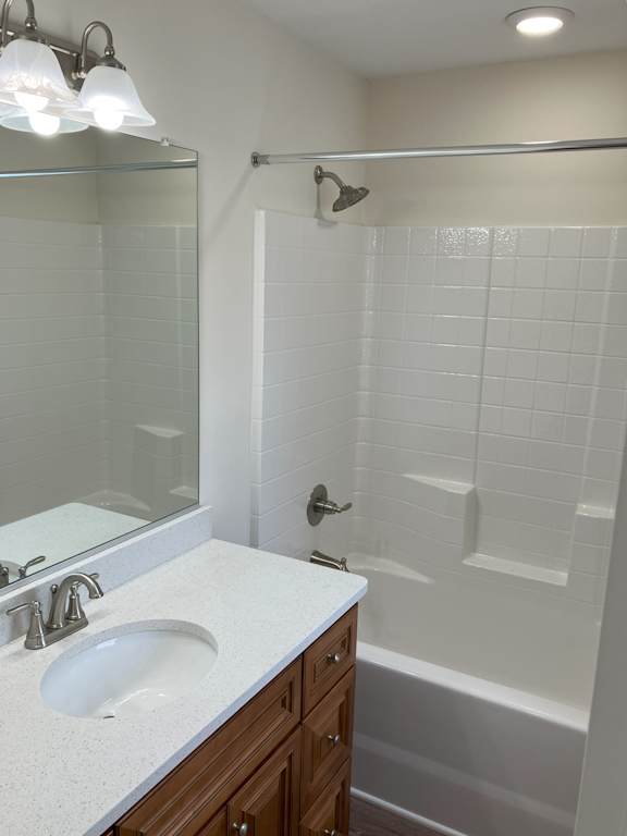A white tiled bathroom with a sink and a bathtub.