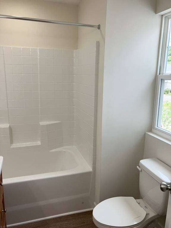 A white toilet sits next to a white bathtub in a bathroom.