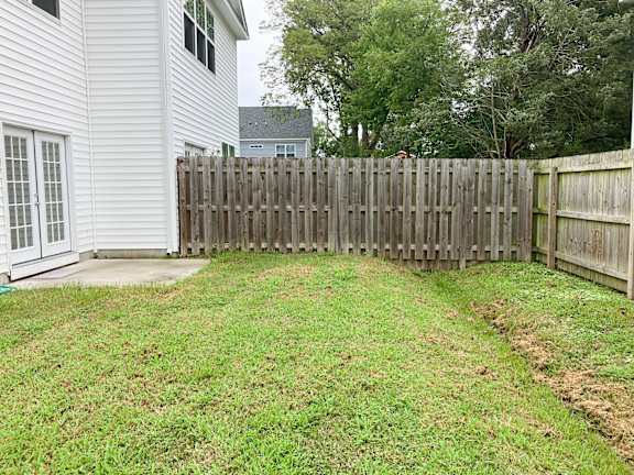 A white house with a wooden fence in the front yard.