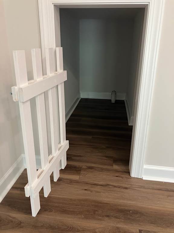 A white railing is on the left side of a hallway.