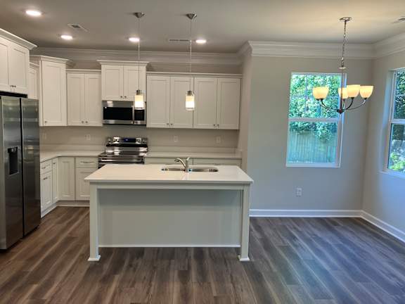 A kitchen with white cabinets and a wooden floor.