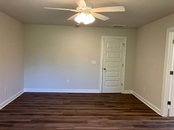 A room with a ceiling fan and wooden flooring.