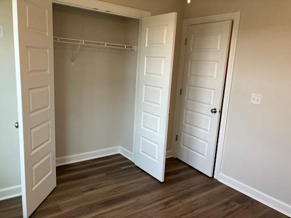 A room with a white door and a white closet with a shelf.