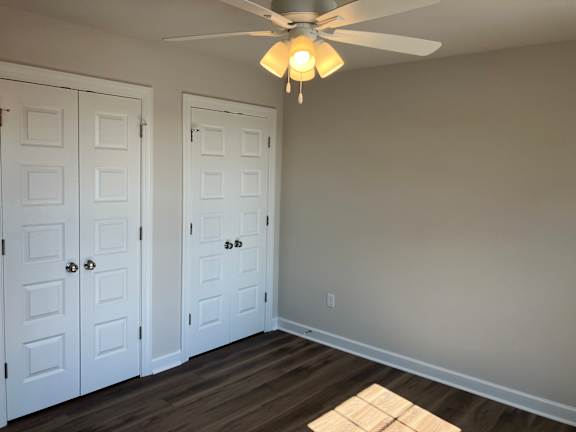 A room with a ceiling fan and two doors.