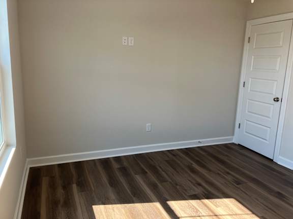 A room with a white door and wooden flooring.