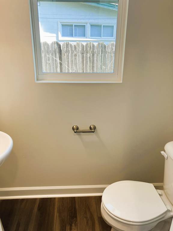 A white toilet in a bathroom with a window.
