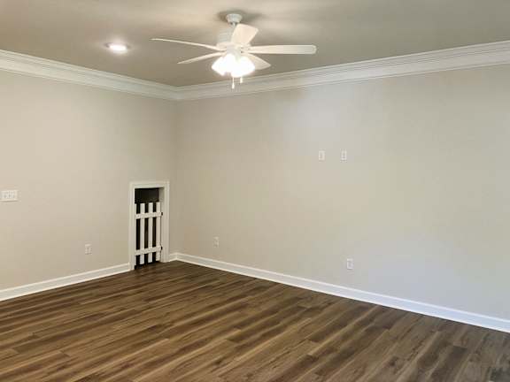 A room with a wooden floor and a white ceiling fan.