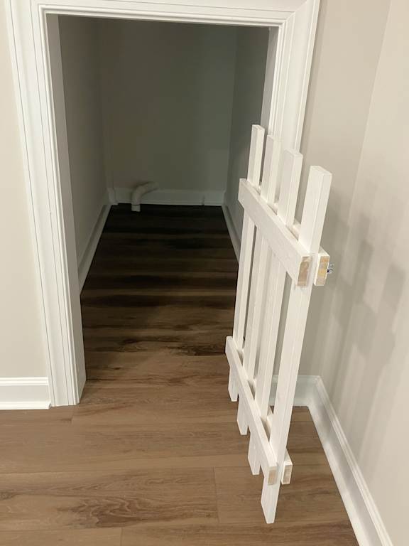 A white railing is on the left side of a hallway.
