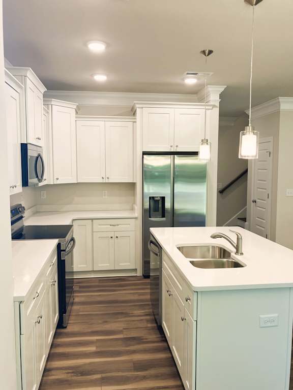 A kitchen with white cabinets and a wooden floor.