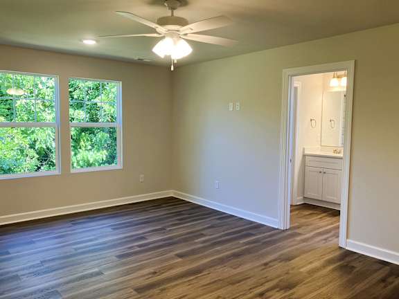 A room with a ceiling fan and wooden flooring.