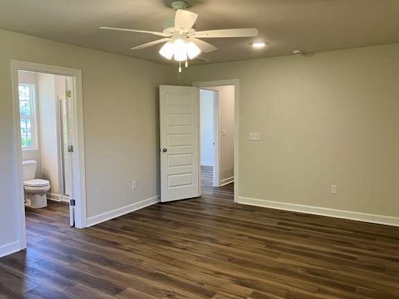 A room with a ceiling fan and wooden flooring.