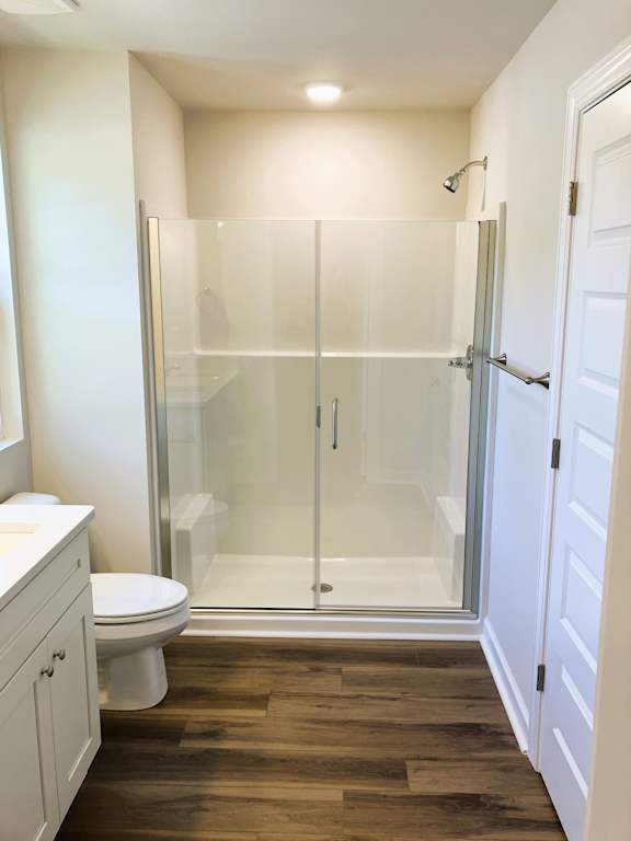 A white toilet sits next to a walk-in shower in a bathroom.