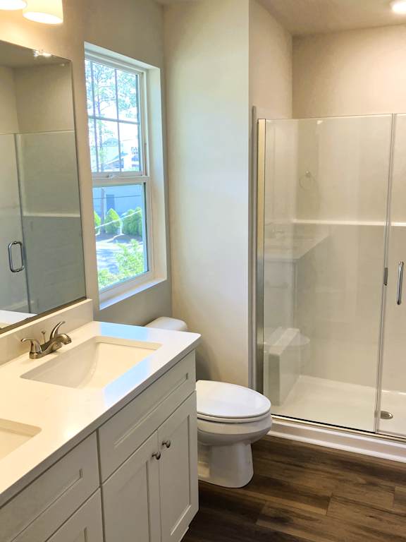A white bathroom with a toilet, sink, and shower.