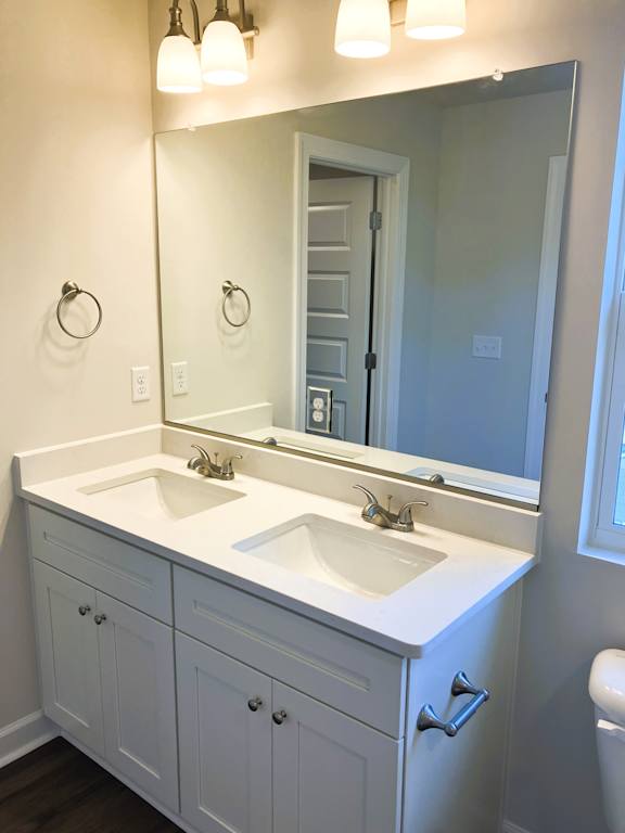 A bathroom with a white vanity and a mirror.