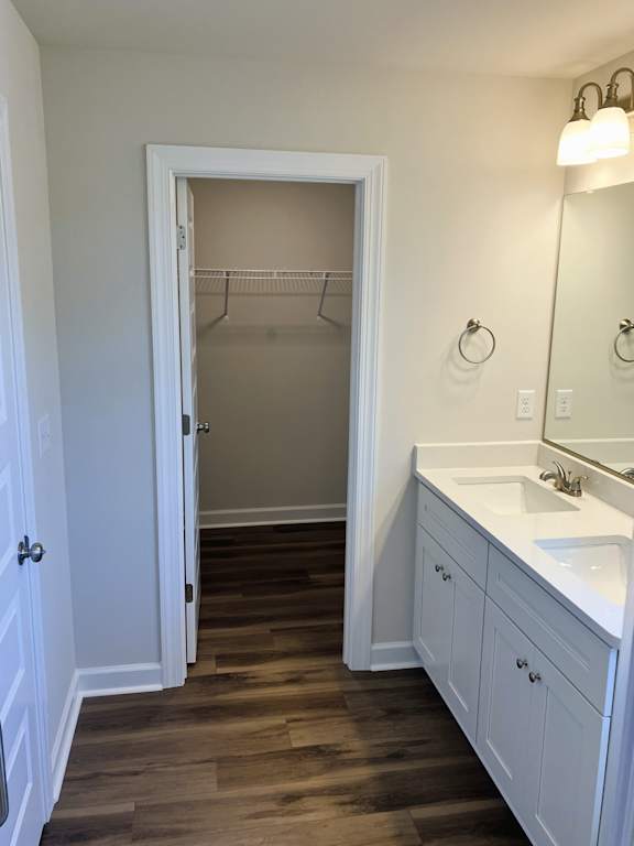 A white bathroom with a wooden floor and a white sink.