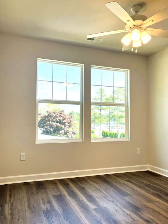 A room with a ceiling fan and two windows.
