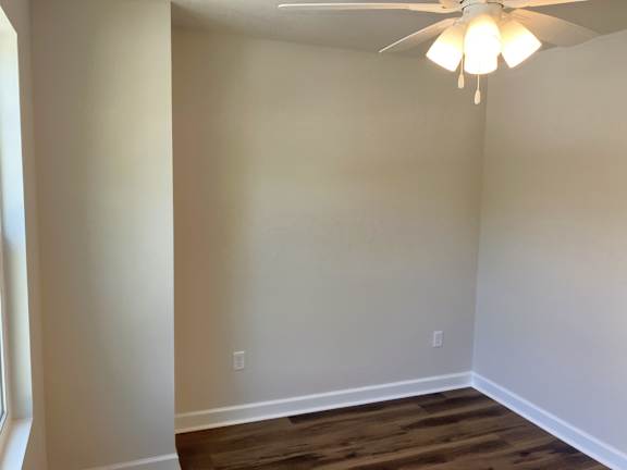 A room with a ceiling fan and wooden flooring.