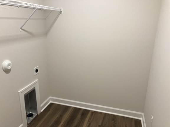 A white wall with a white door and a white shelf.