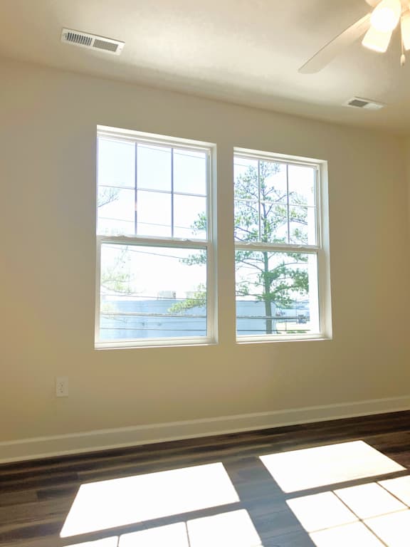A room with two windows and a ceiling fan.