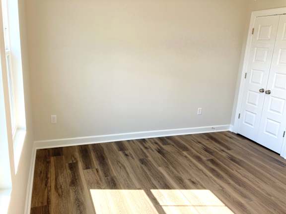 A room with a white door and wooden flooring.
