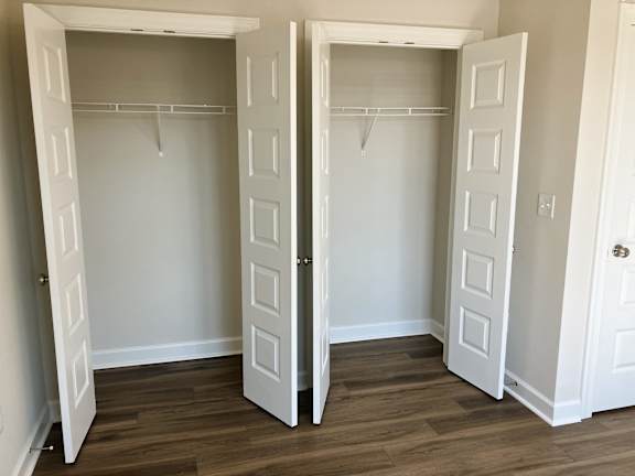 Two white closets with wood floors and white doors.