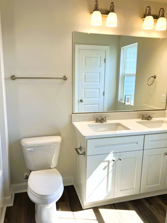 A white toilet sits in a bathroom next to a sink and mirror.