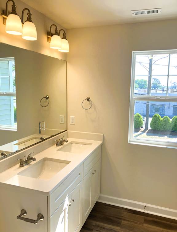 A bathroom with a large mirror and a window.