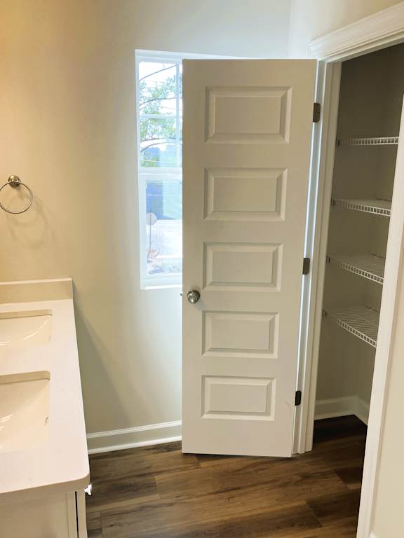 A white door with a white shelf to the left and an open white door to the right.