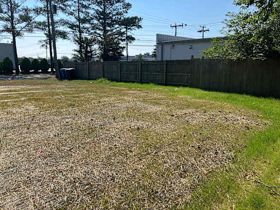 A backyard with a fence and a grassy area.