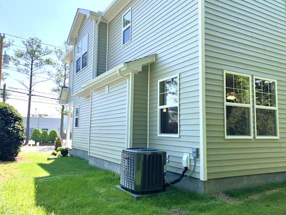 A house with a grey siding and a window with a white frame.