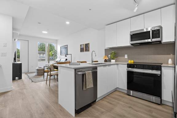A modern kitchen with a wooden floor and white cabinets.
