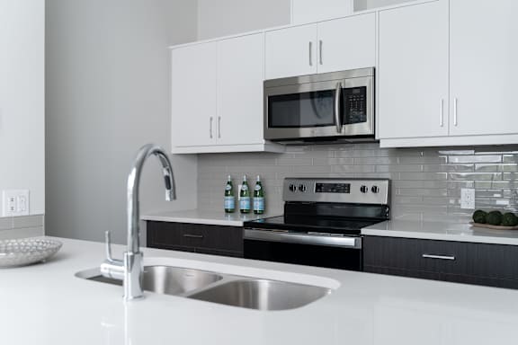 A modern kitchen with a stainless steel sink and a microwave above the stove.