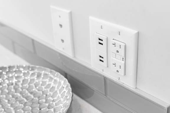 A white electrical outlet with a round object in front of it.