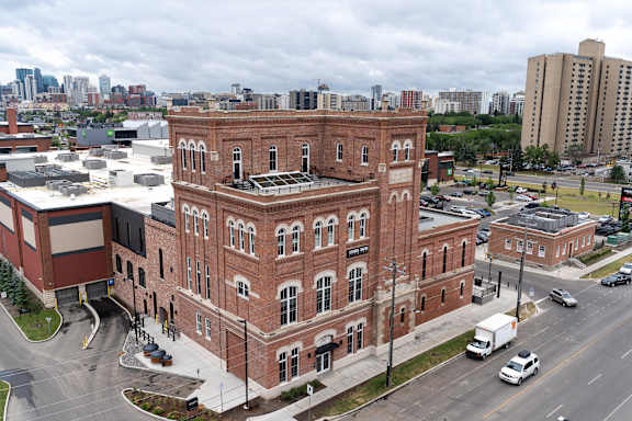 A large red brick building with a flat roof and a parking lot in front of it.