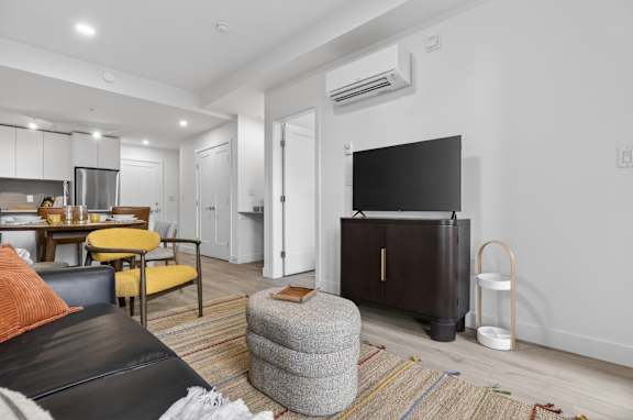 A modern living room with a black leather couch and a grey ottoman.