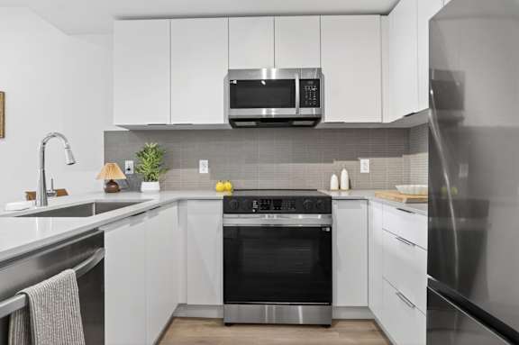 A modern kitchen with a stainless steel oven and white cabinets.