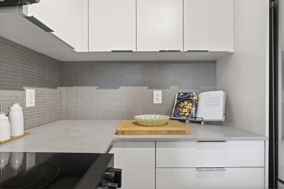 A modern kitchen with white cabinets and a black stove top.
