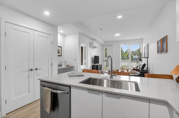 A modern kitchen with a stainless steel sink and white cabinets.